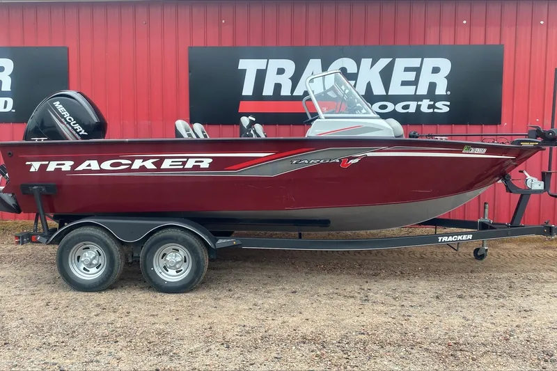 The Image of 2017 Tracker Targa V-18 Combo boat on trailer, red exterior, parked by Tracker Boats sign. - 0