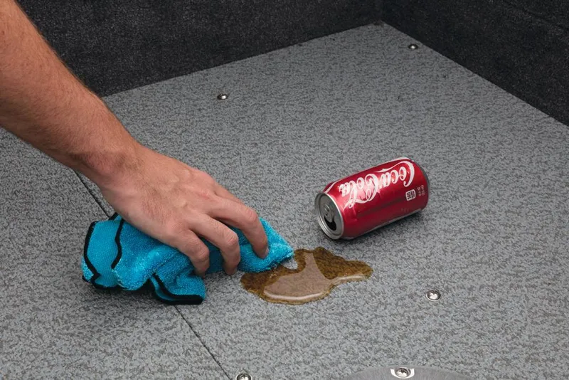 Slide: The Image of A hand wipes spilled cola on a gray carpeted floor with a blue cloth. - 19