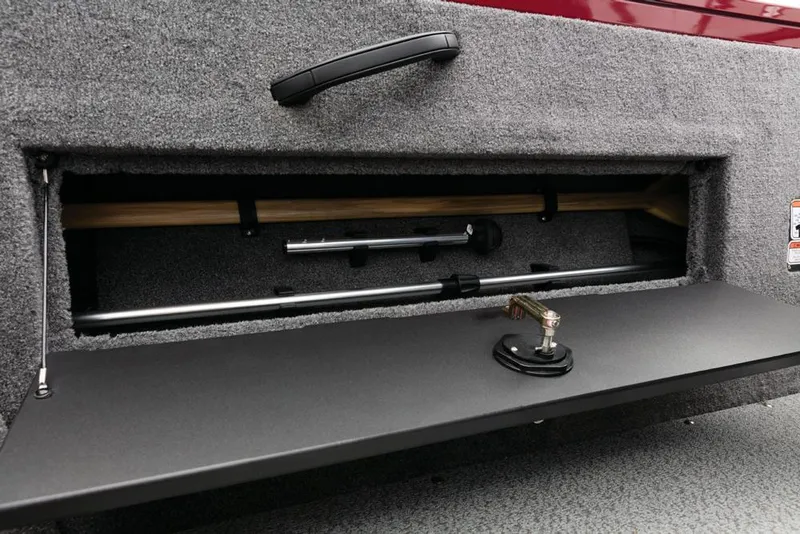 Slide: The Image of An open storage compartment with gray carpeting and a black handle. It contains rods and a bracket. - 31