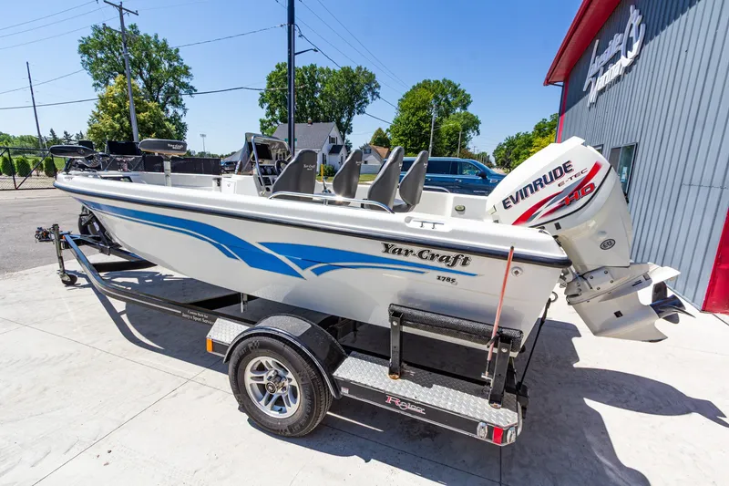 Slide: The Image of 2009 Yarcraft 1785 SC boat with Evinrude motor on trailer, parked outside a building. - 7