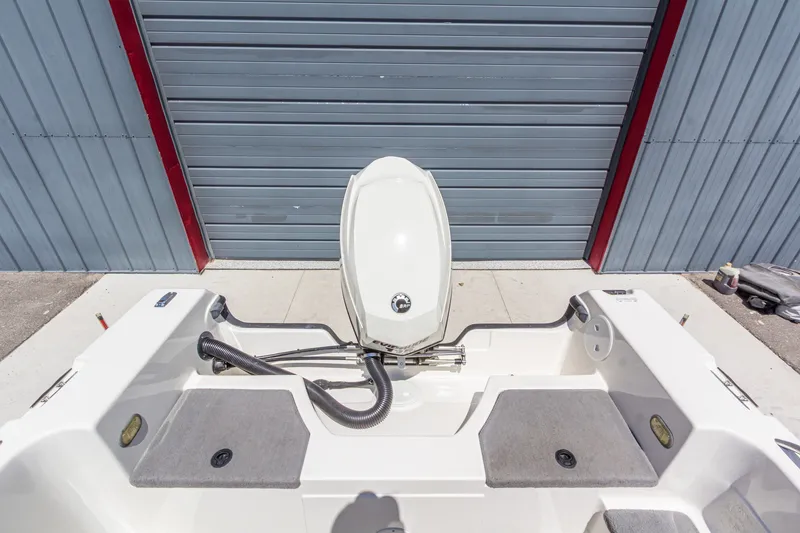 Slide: The Image of 2009 Yarcraft 1785 SC boat with outboard motor, parked near a metal garage door. - 13