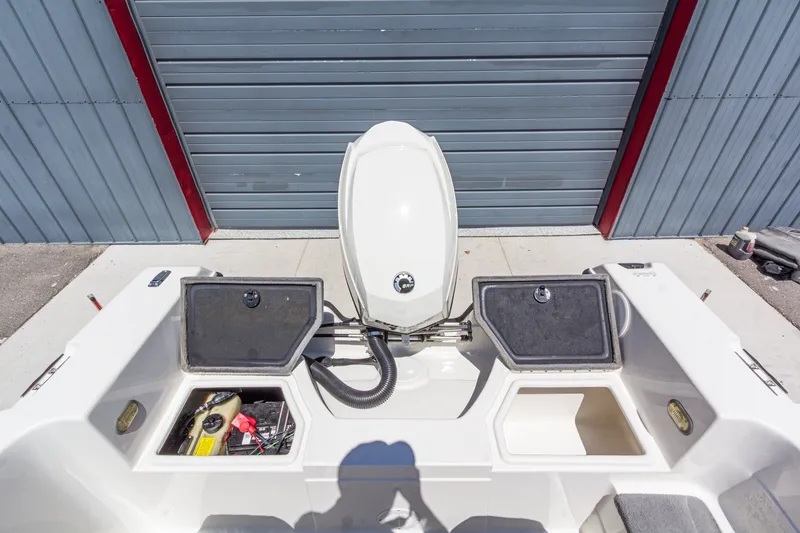 Slide: The Image of 2009 Yarcraft 1785 SC boat with open storage compartments and motor, parked near a garage. - 14