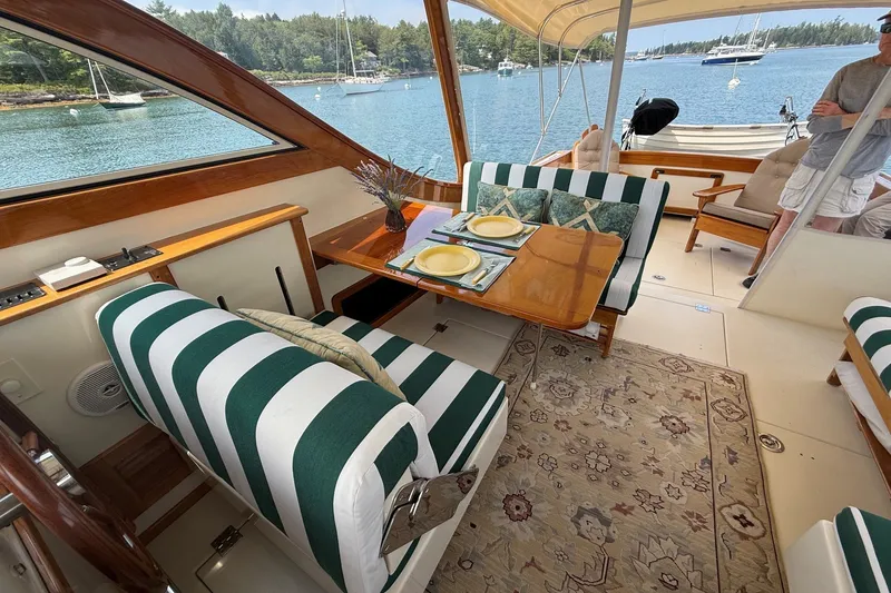 Slide: The Image of Interior of 2003 Ellis 36 Express Cruiser with striped seating and dining area, overlooking serene waters. - 34