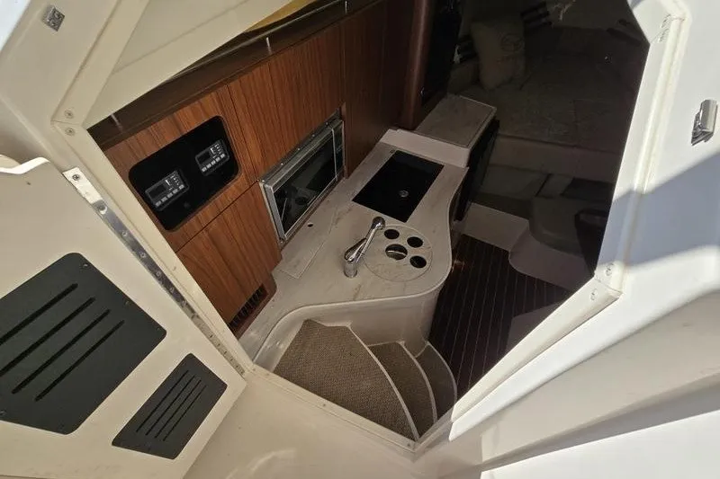Slide: The Image of 2017 Grady-White Express 330 cabin interior with kitchenette and wood paneling. - 16