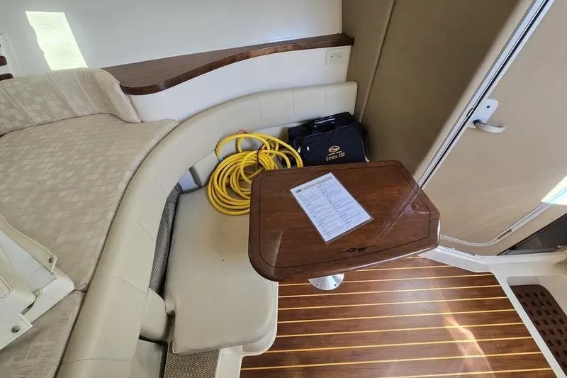 Slide: The Image of Interior of 2017 Grady-White Express 330 boat with seating, table, and coiled yellow cable. - 24