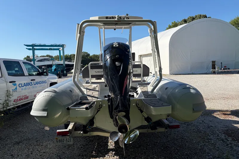 Slide: The Image of 2024 Highfield Sport 660 boat with outboard motor in a marina setting. - 16