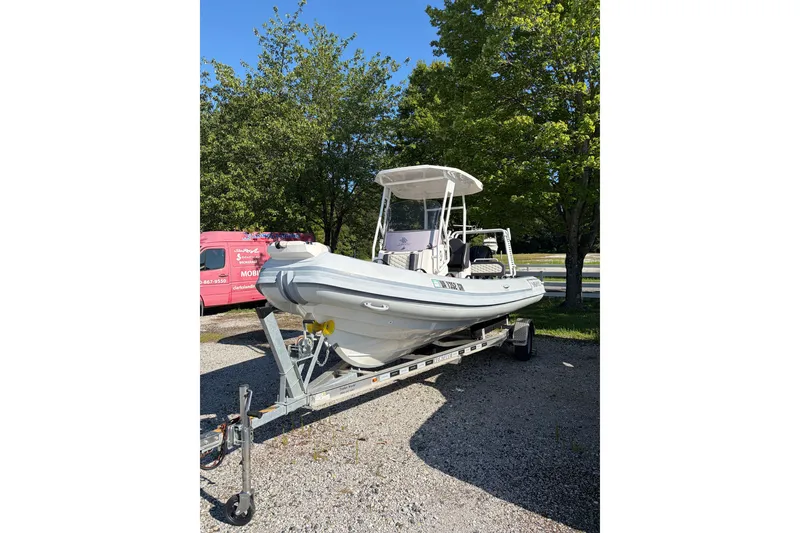 The Image of 2024 Highfield Sport 660 boat on trailer, parked outdoors with trees in background. - 1