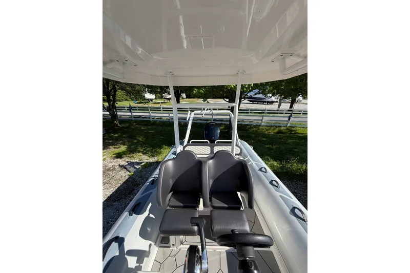 Slide: The Image of 2024 Highfield Sport 660 boat interior with dual seats and canopy, parked outdoors. - 14