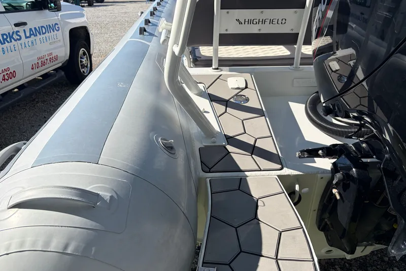 Slide: The Image of 2024 Highfield Sport 660 boat deck with seating and engine, parked outdoors. - 17