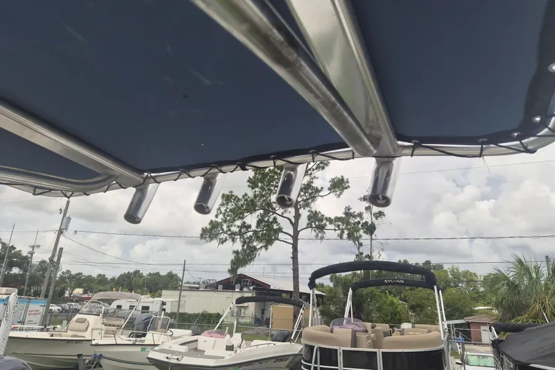 Slide: The Image of 2007 Triumph 190 Bay boat with canopy, docked alongside other boats under cloudy sky. - 14