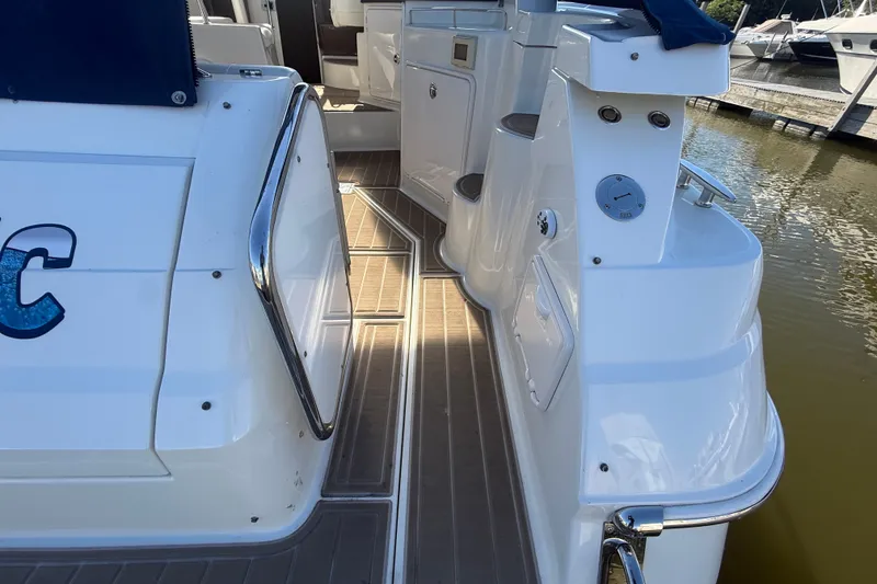 Slide: The Image of 2005 Regal Commodore 3560 IO boat deck, featuring sleek white design and stainless steel railings. - 7