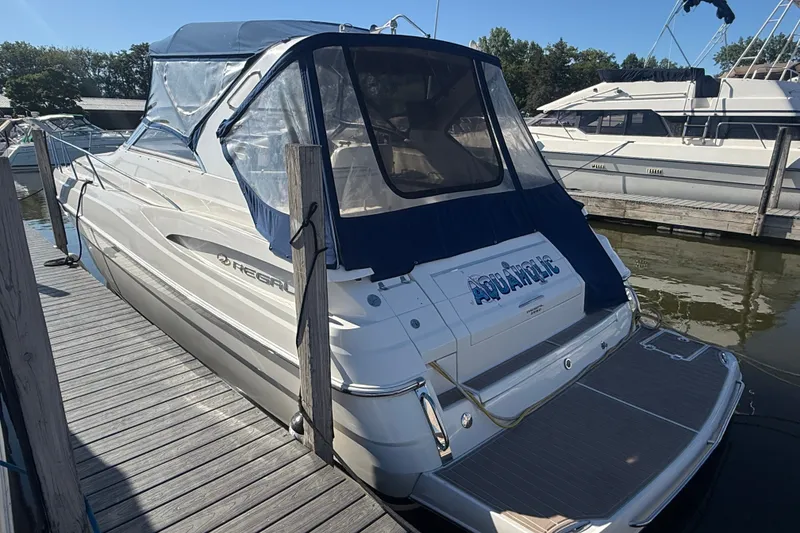 Slide: The Image of 2005 Regal Commodore 3560 IO yacht docked, featuring blue canopy and sleek design. - 2