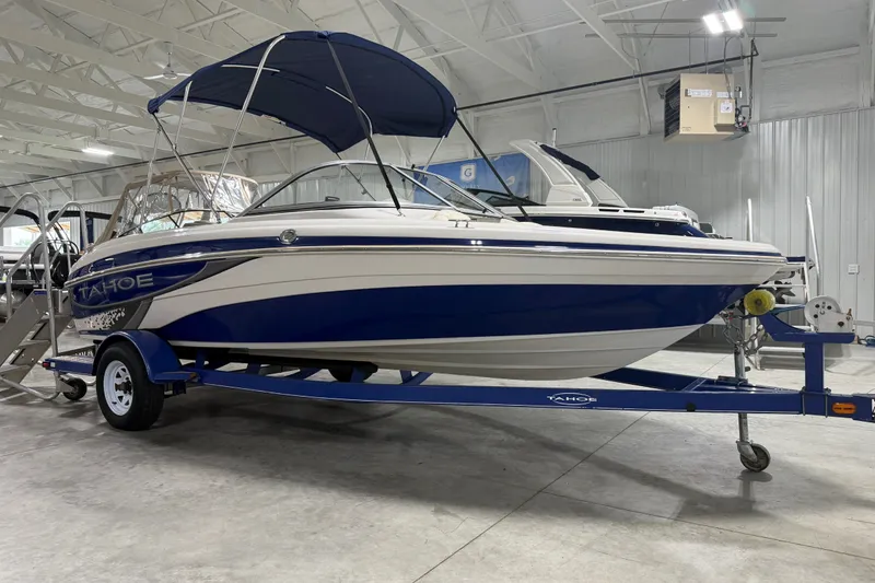Slide: The Image of 2010 Tahoe Q5i Sport boat with blue and white design on trailer in indoor showroom. - 4