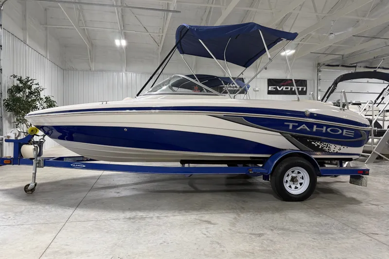 The Image of 2010 Tahoe Q5i Sport boat with blue and white design on trailer in showroom. - 1