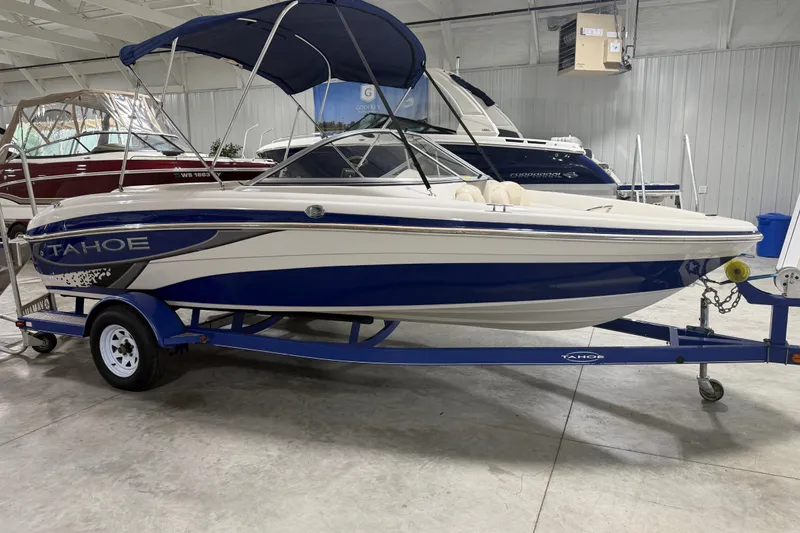 Slide: The Image of 2010 Tahoe Q5i Sport boat with blue and white design on trailer in showroom. - 13