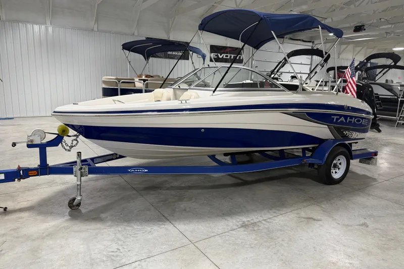 Slide: The Image of 2010 Tahoe Q5i Sport boat on trailer in showroom with American flag. - 14
