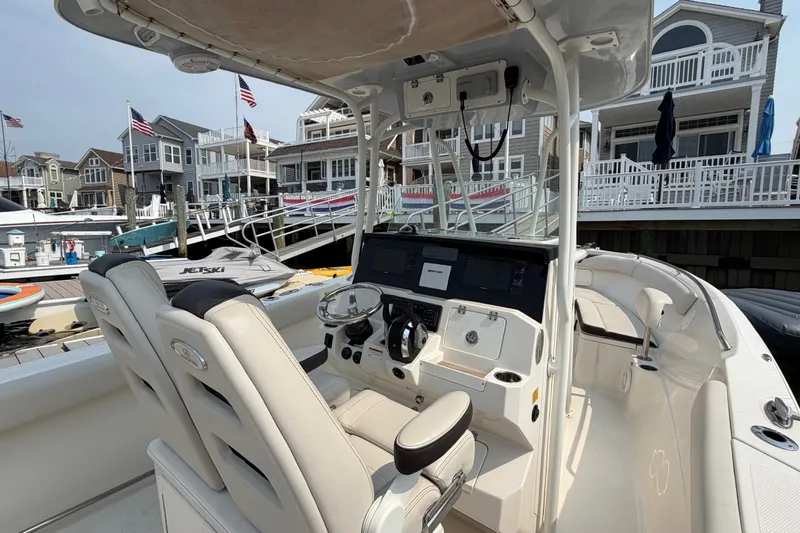 Slide: The Image of 2022 Sailfish 242 CC boat interior at a marina with waterfront homes in the background. - 19