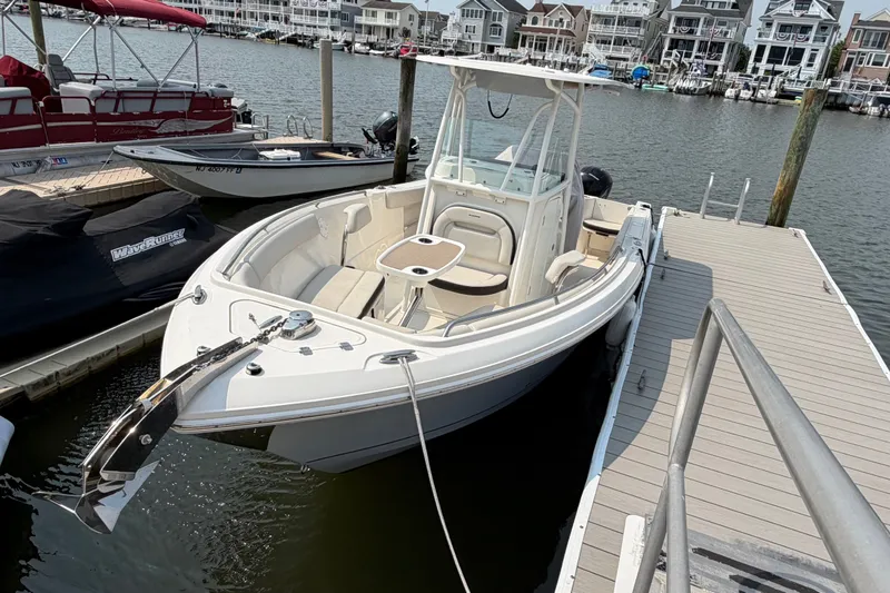 Slide: The Image of 2022 Sailfish 242 CC boat docked at marina with waterfront homes in background. - 2