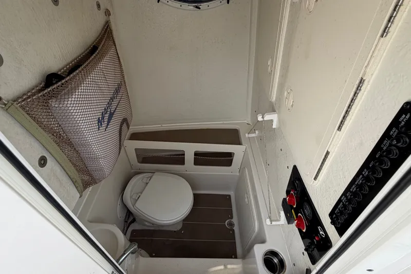 Slide: The Image of Interior of 2022 Sailfish 242 CC boat featuring compact marine toilet and storage. - 24
