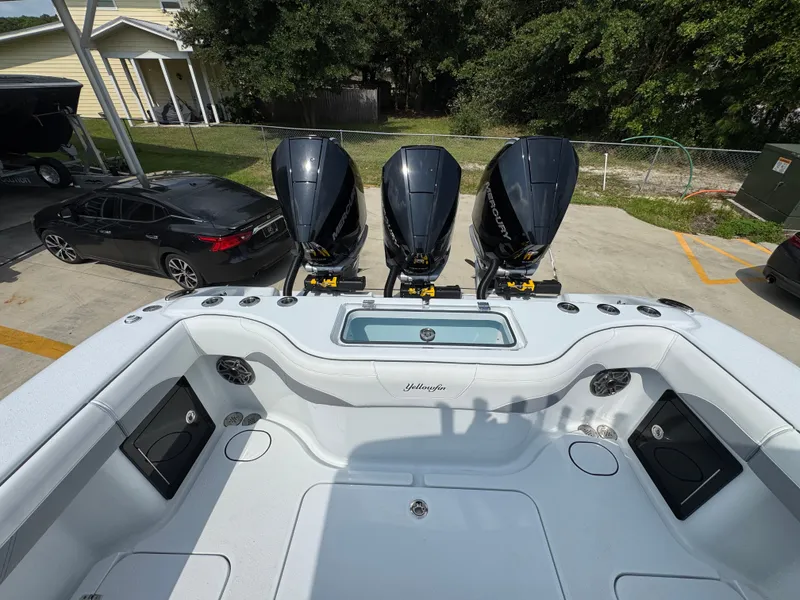 Slide: The Image of 2027 Yellowfin 34 Offshore boat with triple Mercury engines, parked in a driveway. - 46
