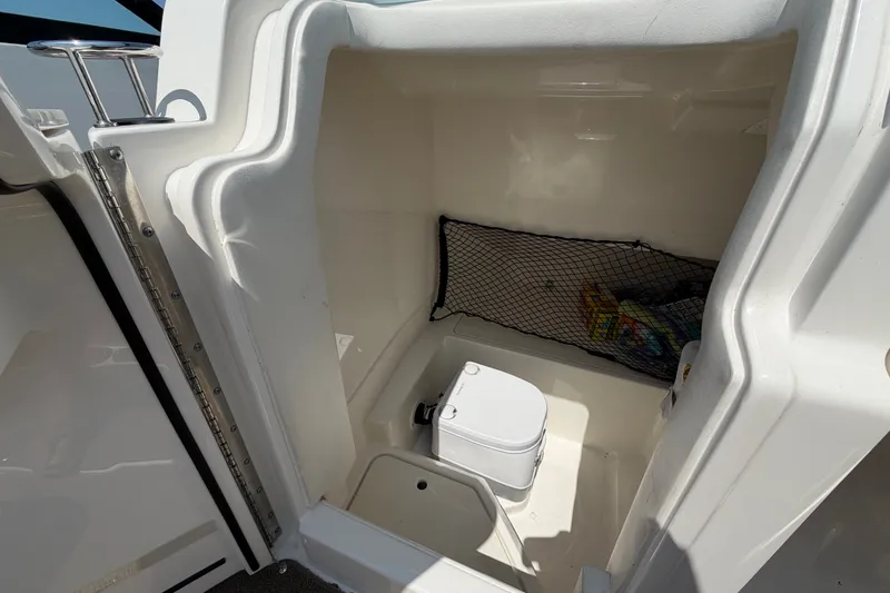 Slide: The Image of 2019 Sea Ray SDX 250 Outboard boat interior with compact toilet and storage net. - 19