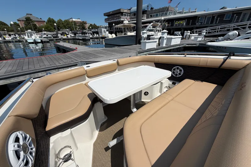 Slide: The Image of 2019 Sea Ray SDX 250 Outboard boat interior with tan seating and white table at marina. - 18