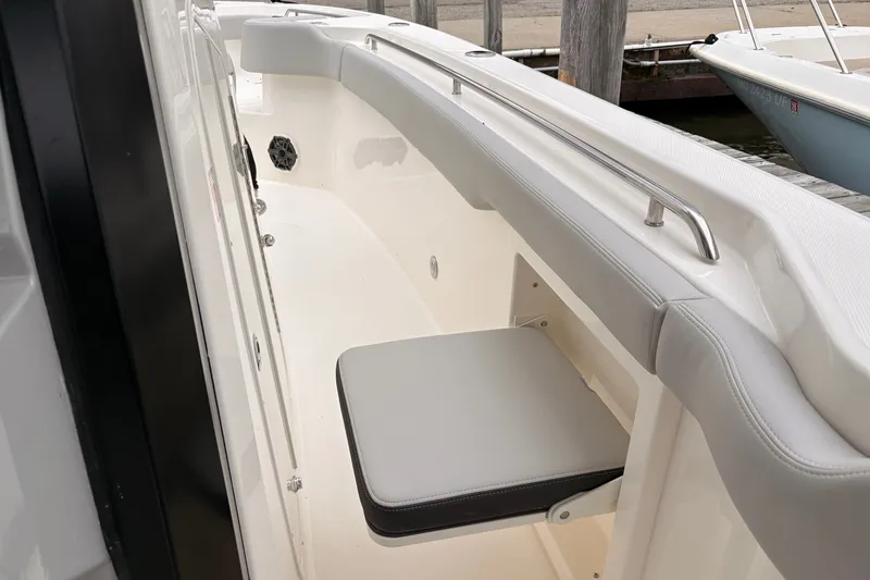Slide: The Image of 2026 Boston Whaler 330 Outrage boat interior with cushioned seating and stainless steel handrail. - 13