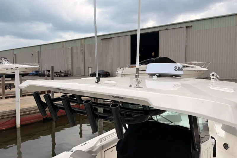 Slide: The Image of 2026 Boston Whaler 330 Outrage docked near a warehouse under cloudy skies. - 20