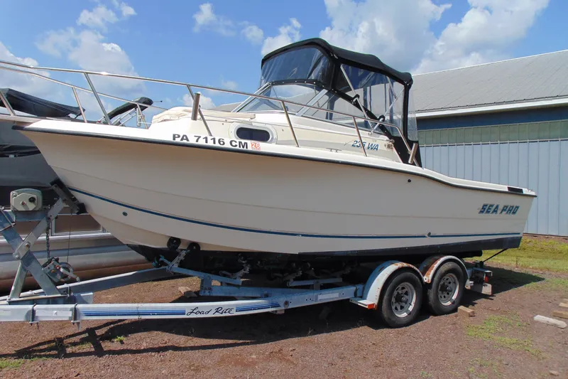 The Image of 1999 Sea Pro boat on trailer, parked outdoors under a clear sky. - 1