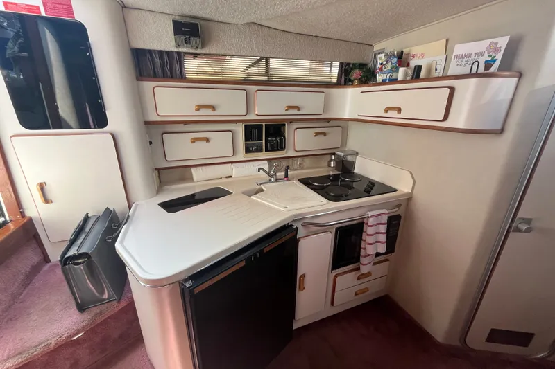 Slide: The Image of 1990 Sea Ray Sundancer 350 yacht kitchen with compact appliances and storage cabinets. - 13