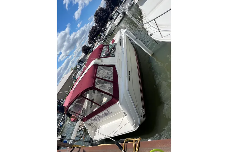 Slide: The Image of 1990 Sea Ray Sundancer 350 docked, featuring maroon canopy and clear skies. - 18