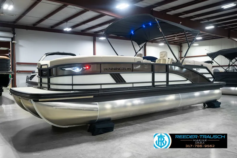 Slide: The Image of 2026 Bennington 24 MSB pontoon boat in showroom with canopy and sleek design. - 2
