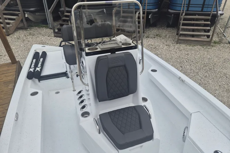 Slide: The Image of 2027 Xpress H20B Bay boat interior with cushioned seating and console, docked outdoors. - 15