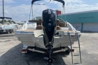 Slide: The Image of 2023 Crownline Eclipse E215 XS boat with outboard motor and ladder, parked outdoors. - 6