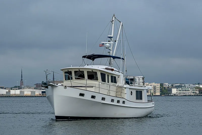 Slide: The Image of 2008 Krogen 48 North Sea yacht cruising near urban waterfront under cloudy skies. - 12