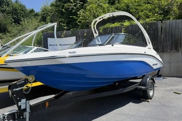 The Image of 2024 Yamaha Boats AR195 in blue and white on a trailer, parked outdoors. - 1