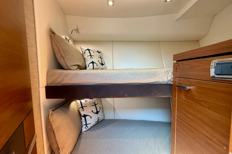 Slide: The Image of Cozy bunk beds in 2015 Tiara Yachts 50 Coupe cabin with nautical-themed pillows. - 70