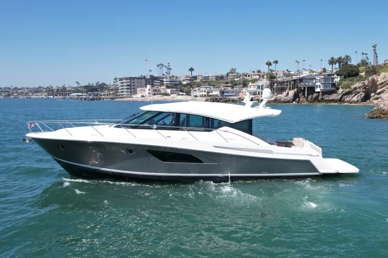 The Image of 2015 Tiara Yachts 50 Coupe cruising near coastal homes on a sunny day. - 0