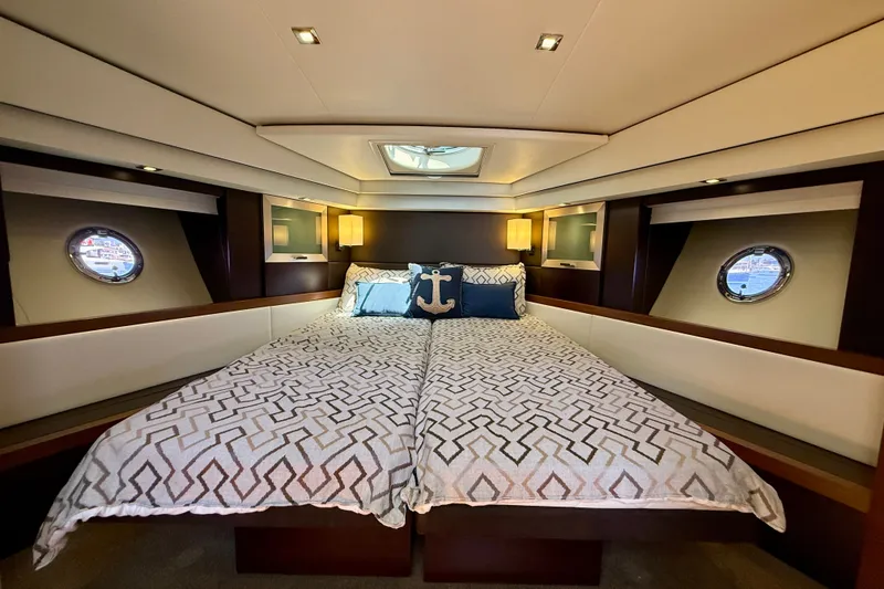 Slide: The Image of Luxurious bedroom interior of 2015 Tiara Yachts 50 Coupe with elegant bedding and porthole windows. - 59