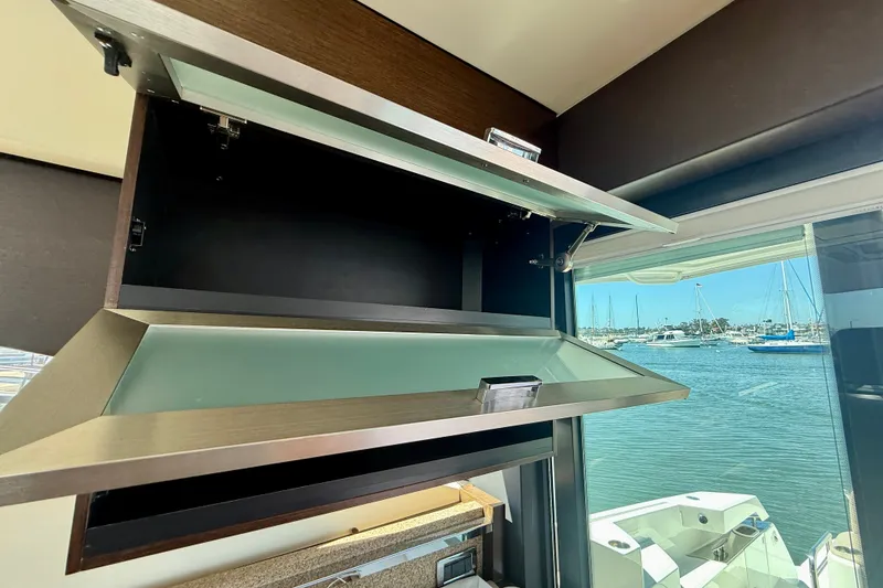 Slide: The Image of Interior view of 2015 Tiara Yachts 50 Coupe with open cabinet and marina backdrop. - 26
