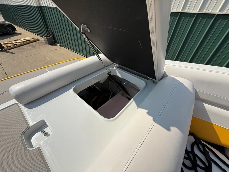Slide: The Image of An open storage compartment on a 2015 Crownline 235 SS boat, featuring white upholstery. - 24