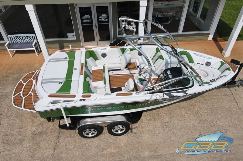 Slide: The Image of 2008 Nautique Super Air Nautique 210 boat with green accents, parked on a trailer. - 17