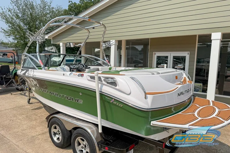 Slide: The Image of 2008 Nautique Super Air Nautique 210 boat in green and white, parked on a trailer. - 2
