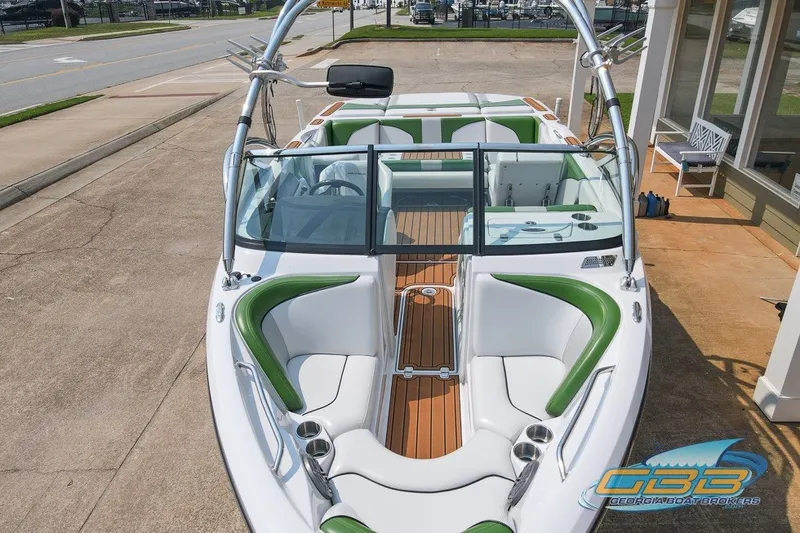 Slide: The Image of 2008 Nautique Super Air Nautique 210 boat with green and white interior, docked on pavement. - 14