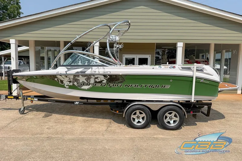 Slide: The Image of 2008 Nautique Super Air Nautique 210 boat on trailer, green and white design. - 1