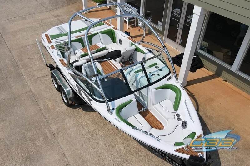 Slide: The Image of 2008 Nautique Super Air Nautique 210 boat with green accents, parked on a trailer. - 16