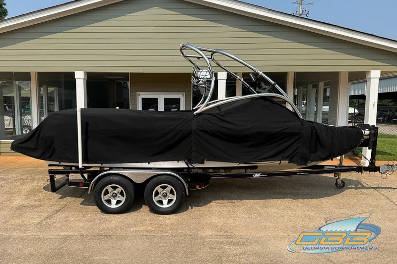 Slide: The Image of 2008 Nautique Super Air Nautique 210 boat covered on trailer outside a building. - 29
