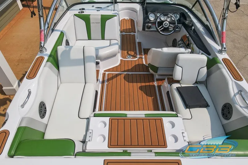 Slide: The Image of 2008 Nautique Super Air Nautique 210 boat interior with green and white seating, wood accents. - 11