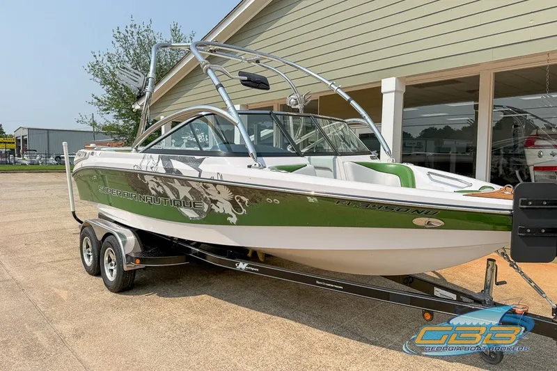 Slide: The Image of 2008 Nautique Super Air Nautique 210 boat on trailer, green and white design, parked outdoors. - 4