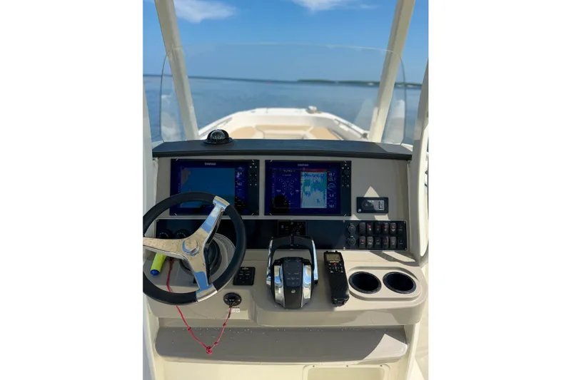 Slide: The Image of 2017 Boston Whaler 270 Dauntless helm with navigation screens and steering wheel on open water. - 13